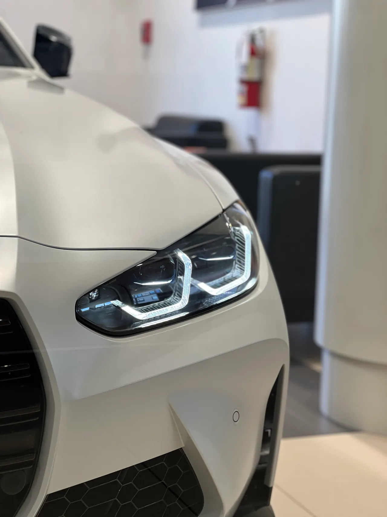 Headlight detail of a white sports car in a showroom