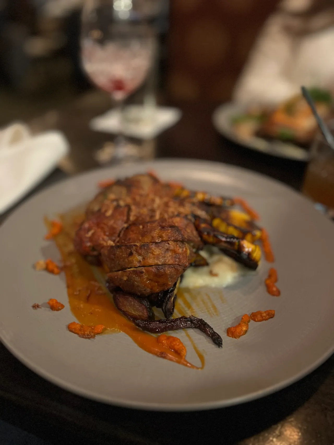 Plated entree with sauce on a grey dish at a restaurant table