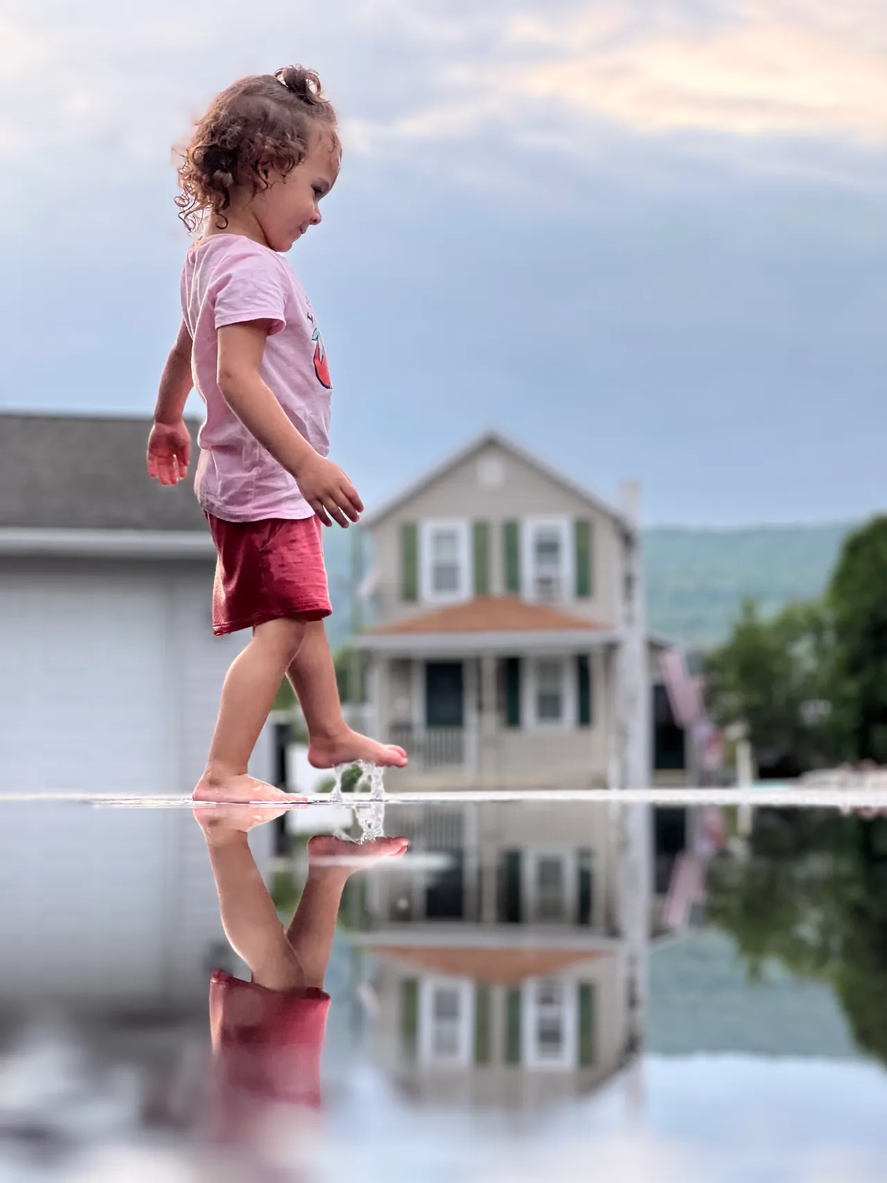 Toddler walking along a reflective puddle at dusk